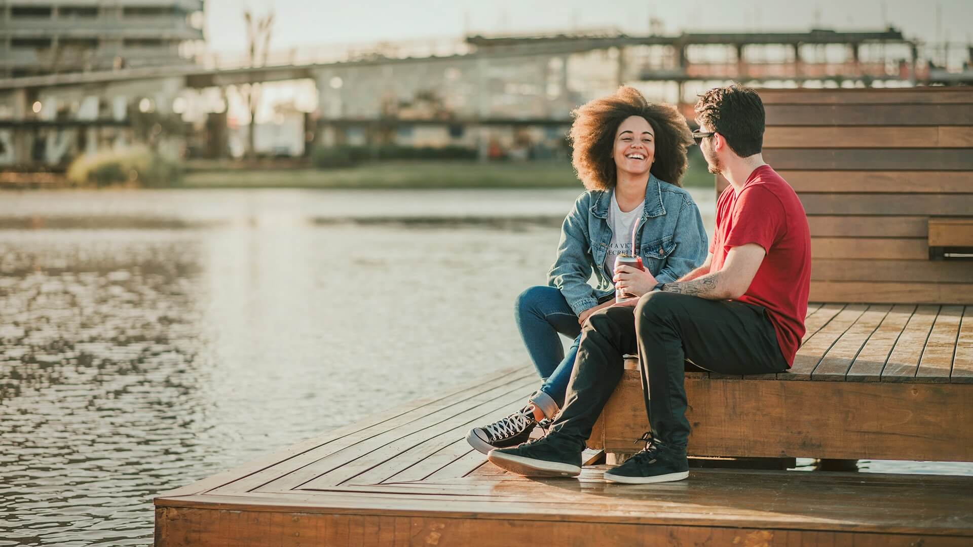 Casal conversando em deck de madeira à beira do lago no Parque Una Pelotas